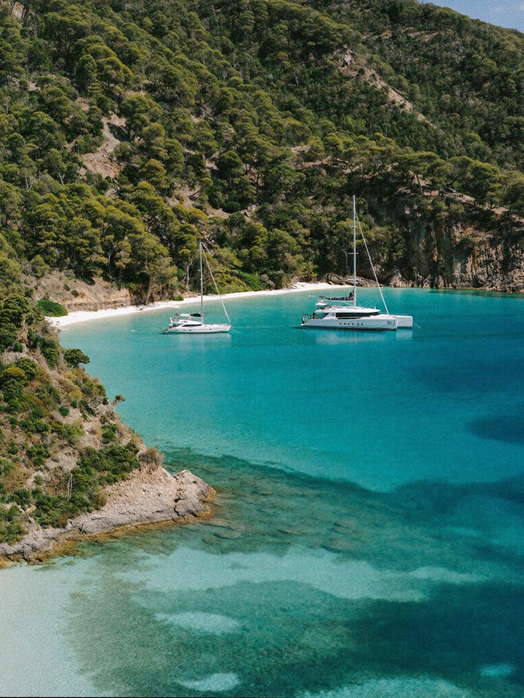 Turquoise cove with pine-covered cliffs and sailing boats at Cala Formentor, Mallorca