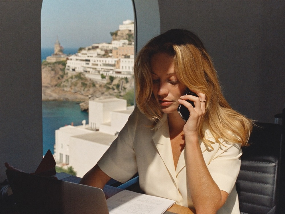 A Viva Mortgages Spain advisor reviewing paperwork on a call, overlooking a Mediterranean coastal town